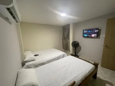 a room with two beds and a flat screen tv at Villa Carolina SM in Santa Marta