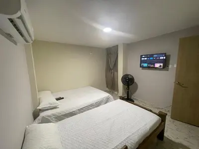a bedroom with two beds and a flat screen tv at Villa Carolina SM in Santa Marta