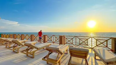 a man standing on a deck watching the sunset at SUITE OCEAN VIEW - Playa in Tolú