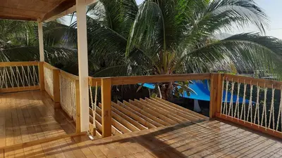 a porch with a wooden railing and a palm tree at KAZA Balcones in Santa Veronica