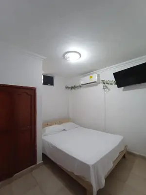 a white bedroom with a bed and a tv at Hostal Miami Beach in Cartagena de Indias