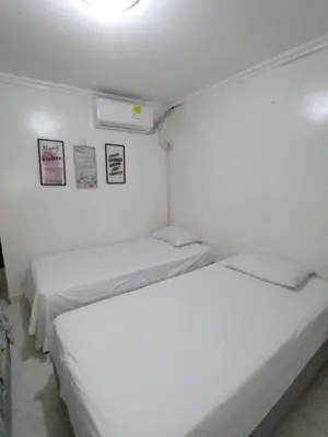 two beds in a small room with white walls at Hostal Miami Beach in Cartagena de Indias