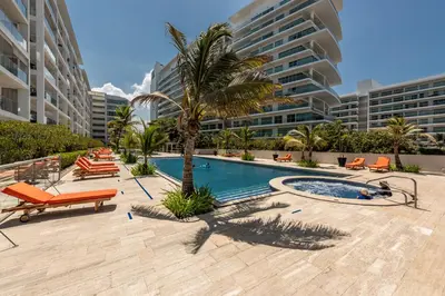 a pool with chairs and a palm tree and buildings at Edificio Morros 3 in Cartagena de Indias