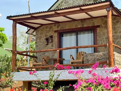 a stone house with rocking chairs and flowers at Ecohotel Summer Usiacuri in Usiacurí