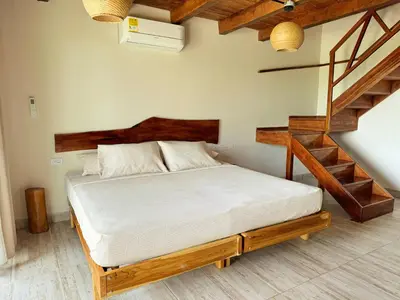 a bedroom with a bed with a wooden frame and stairs at Ecohotel Summer Usiacuri in Usiacurí