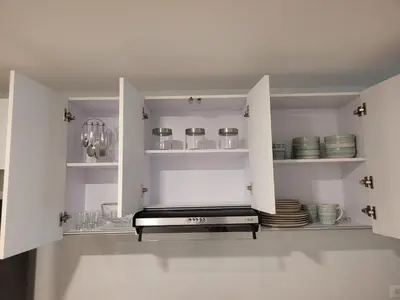 a kitchen with white cabinets with plates and bowls at Apartamento cerca al Mar in Cartagena de Indias