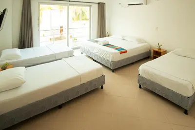 a room with three beds and a window at Hotel Caribe Coveñas in Coveñas