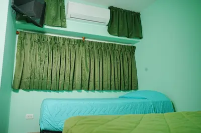 a bedroom with a bed and a window with green curtains at Frente al mar, Boca grande APT1105 in Cartagena de Indias