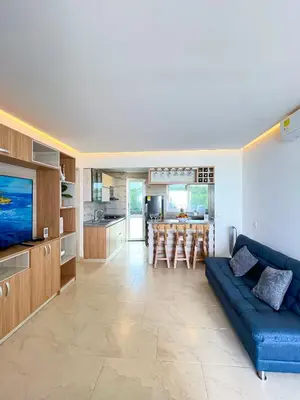 a living room with a blue couch and a kitchen at Hermosa Suite frente al mar en Tolu-Sucre in San Silvestre