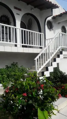 a white house with a staircase and a bush at B&B Grand Royal Inn in Barranquilla