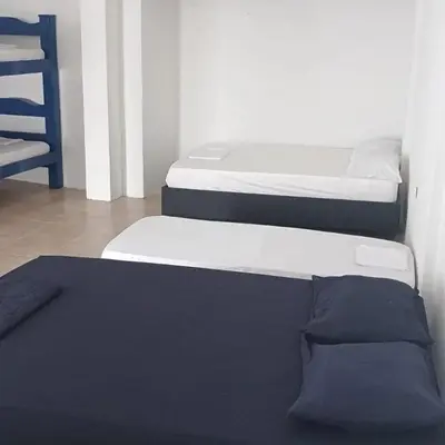 two twin beds in a room with a chair at Cabaña Palma Azul in Coveñas