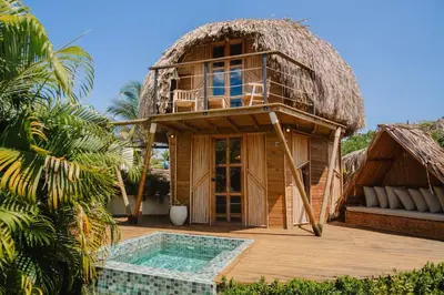 a resort with a thatched building with a pool at JERUSALEMA BEACH GLAMPING in Tolú
