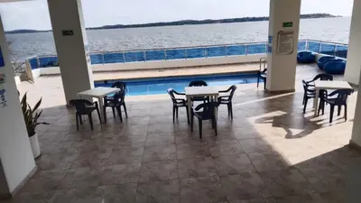 a room with tables and chairs next to the water at A un paso del mar in Cartagena de Indias