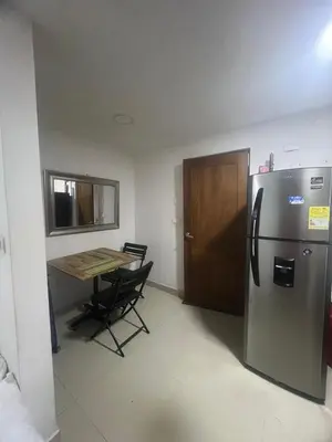 a kitchen with a refrigerator and a table with a chair at A un paso del mar in Cartagena de Indias