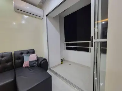 a living room with a black leather couch and a window at Apartamento cerca al Mar, en Cartagena COL in Cartagena de Indias