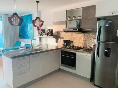 a kitchen with white cabinets and a stainless steel refrigerator at Apartament Bocagrande Palmetto Beach Front 3204 in Cartagena de Indias