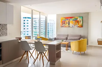 a kitchen and living room with a table and yellow chairs at Apartamento 2 dormitorios Morros Vistas. Piscina in Cartagena de Indias