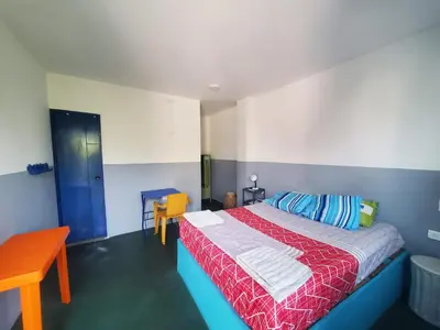 a bedroom with a bed with a red and blue blanket at Hotelito La Aventura, AC private WC rooms near the old town, no tax in Cartagena de Indias