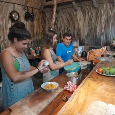 a group of people standing in a kitchen preparing food at Hostel Nugeku in Rincón