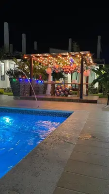 a building with lights and a swimming pool at night at Cabaña Villa Linda in Juan de Acosta
