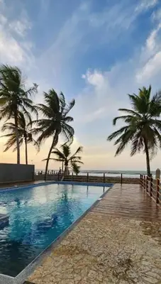 a swimming pool with palm trees next to the beach at Apto PB Palmar de los vientos in San Bernardo del Viento