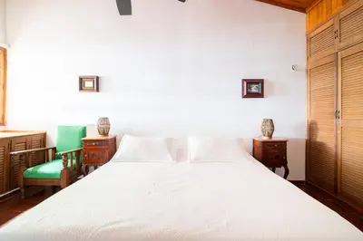 a bedroom with a white bed and two chairs at El Refugio Beach House, Bello Horizonte, Santa Marta in Playa Dormida
