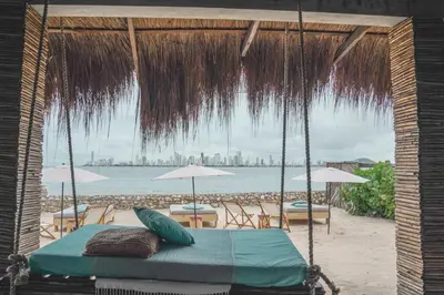 a swing on the beach with chairs and umbrellas at Namaste Beach Club & Hotel in Tierra Bomba