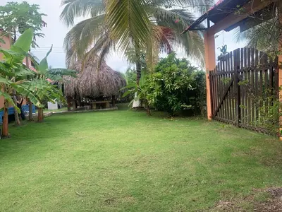 a yard with a grass hut and a yard with green grass at Cabaña El Esplendor in San Bernardo del Viento