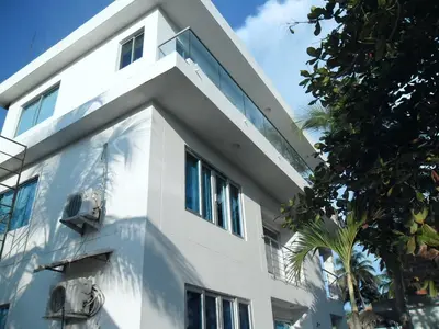 a white building with a palm tree in front of it at Villa Patry Coveñas in Coveñas