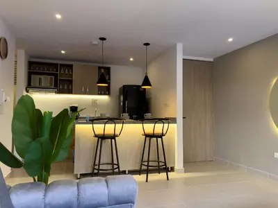 a kitchen with a bar and stools in a room at Lujoso apartamento cerca al Aeropuerto y Ciudad Amurallada in Cartagena de Indias