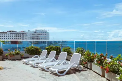 a row of white lounge chairs sitting on a roof at Sunshine 503 Beautiful SeaView 2Beds2bath w AC front Beach in Cartagena de Indias