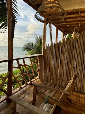 a wooden porch with a chair on the beach at Cabaña Punta Coral in Rincón