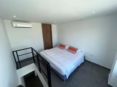 a bedroom with a bed with white sheets and red pillows at Apartamento Duplex en Barranquilla in Barranquilla