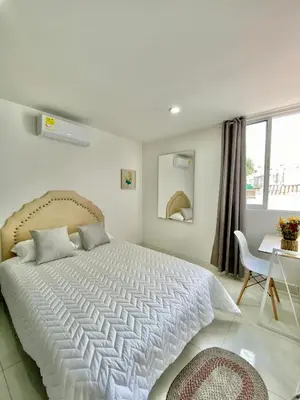 a bedroom with a large white bed and a desk at Casa Jardin in Cartagena de Indias
