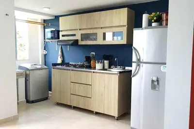 a kitchen with wooden cabinets and a white refrigerator at Apartamento familiar en Coveñas in Coveñas