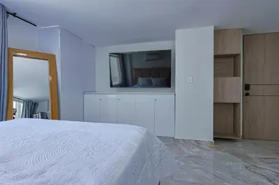 a bedroom with a white bed and a tv on a wall at Lujoso Apartamento con salida a la playa in Cartagena de Indias