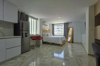 a bedroom with a bed and a kitchen with a refrigerator at Lujoso Apartamento con salida a la playa in Cartagena de Indias