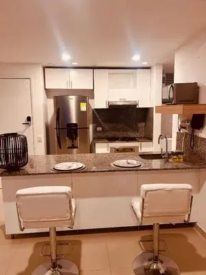 a kitchen with white cabinets and two bar stools at Morros EPIC OCEAN AND BEACH in Cartagena de Indias
