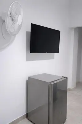 a white wall with a flat screen tv and a fan at Maos flats-Habitacion comfort in Cartagena de Indias
