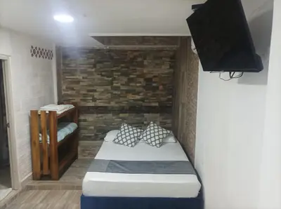 a small bedroom with a bed and a tv at Hostal Catalleya in Cartagena de Indias