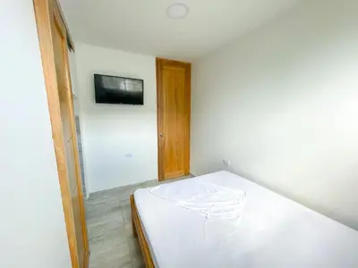 a white bed in a room with a tv on the wall at Apartamento Villa Carolina 102 in Coveñas