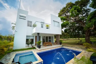 a white house with a swimming pool in front of it at Cabaña Villa July in Moñitos