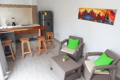 a living room with chairs and a kitchen with a counter at Apartamento Villa Carolina 101 in San Antero