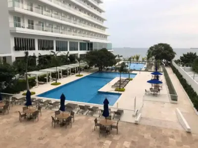 a swimming pool with tables and chairs and a building at Edificio Playa dormida 2 con Piscina y playa in Santa Marta