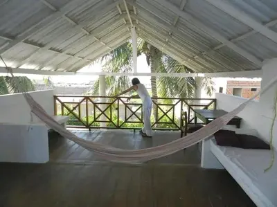 a person standing in a hammock on a porch at La Boquilla, Cartagena, Hospedaje, Turismocolombia-fit in Cartagena de Indias