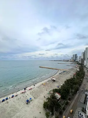 a beach with people and umbrellas and the ocean at Beachfront Luxurious Apartment, Palmetto Beach in Cartagena de Indias