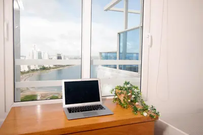 a laptop sitting on a wooden table in front of a window at Riviera Sunrise Beach - Frente al mar y vista panorámica a toda la ciudad in Cartagena de Indias