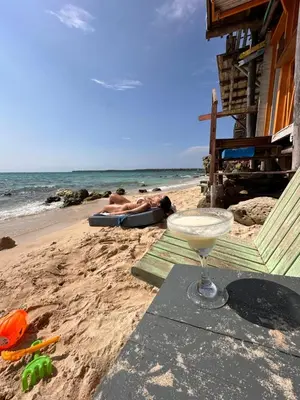 a drink on the beach with people laying on the beach at Itaca Eco House in Playa Blanca