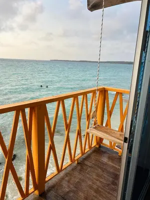 a porch swing overlooking the ocean with people in the water at Itaca Eco House in Playa Blanca