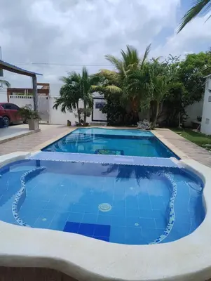 a large blue swimming pool with palm trees in the background at Cabaña campestre Villa Liliana in Juan de Acosta